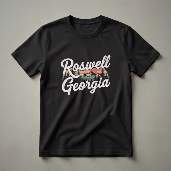 Black t-shirt with a retro graphic design featuring the words 'Roswell Georgia' in distressed white script over a vintage sunset, mountains, and pine trees.