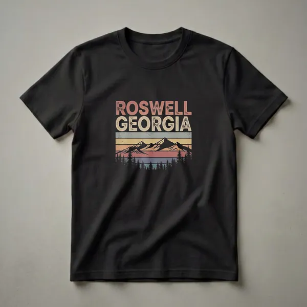 Black t-shirt with a retro graphic design that reads "ROSWELL GEORGIA" above a mountain range and pine trees, set against a striped sunset.