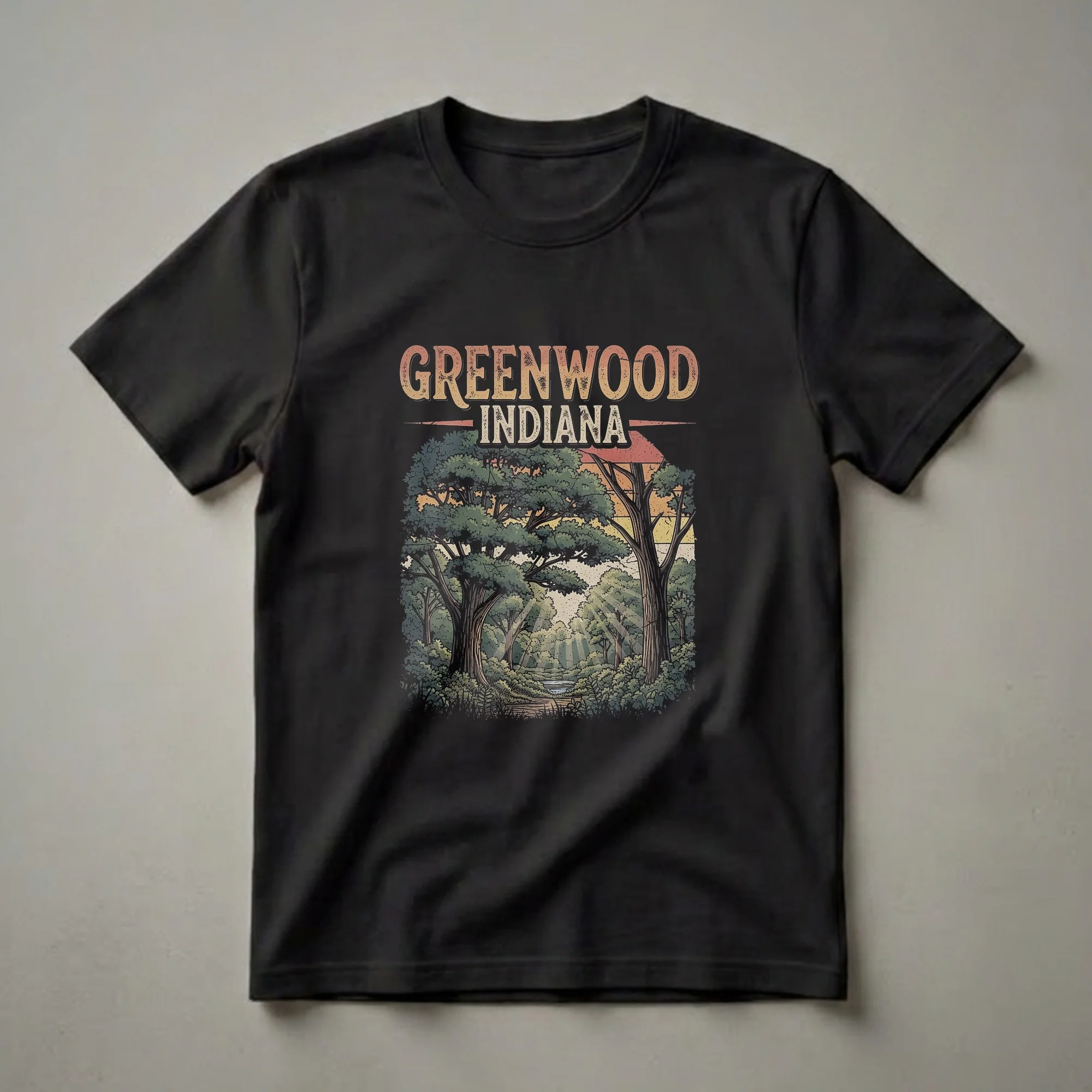 Black t-shirt with a retro graphic design that reads "GREENWOOD INDIANA" above a detailed illustration of a forest with trees, foliage, a creek, and sunbeams.