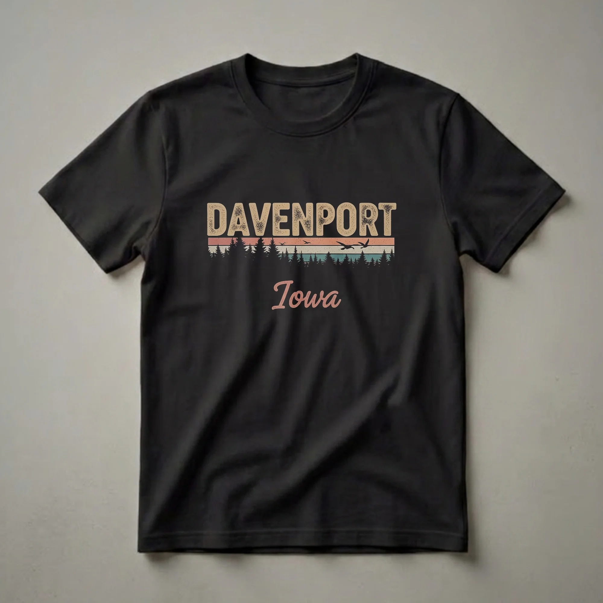 Black t-shirt with a retro design featuring the word DAVENPORT in distressed beige letters, a striped sunset with silhouetted pine trees and flying birds, and the word Iowa in script below.
