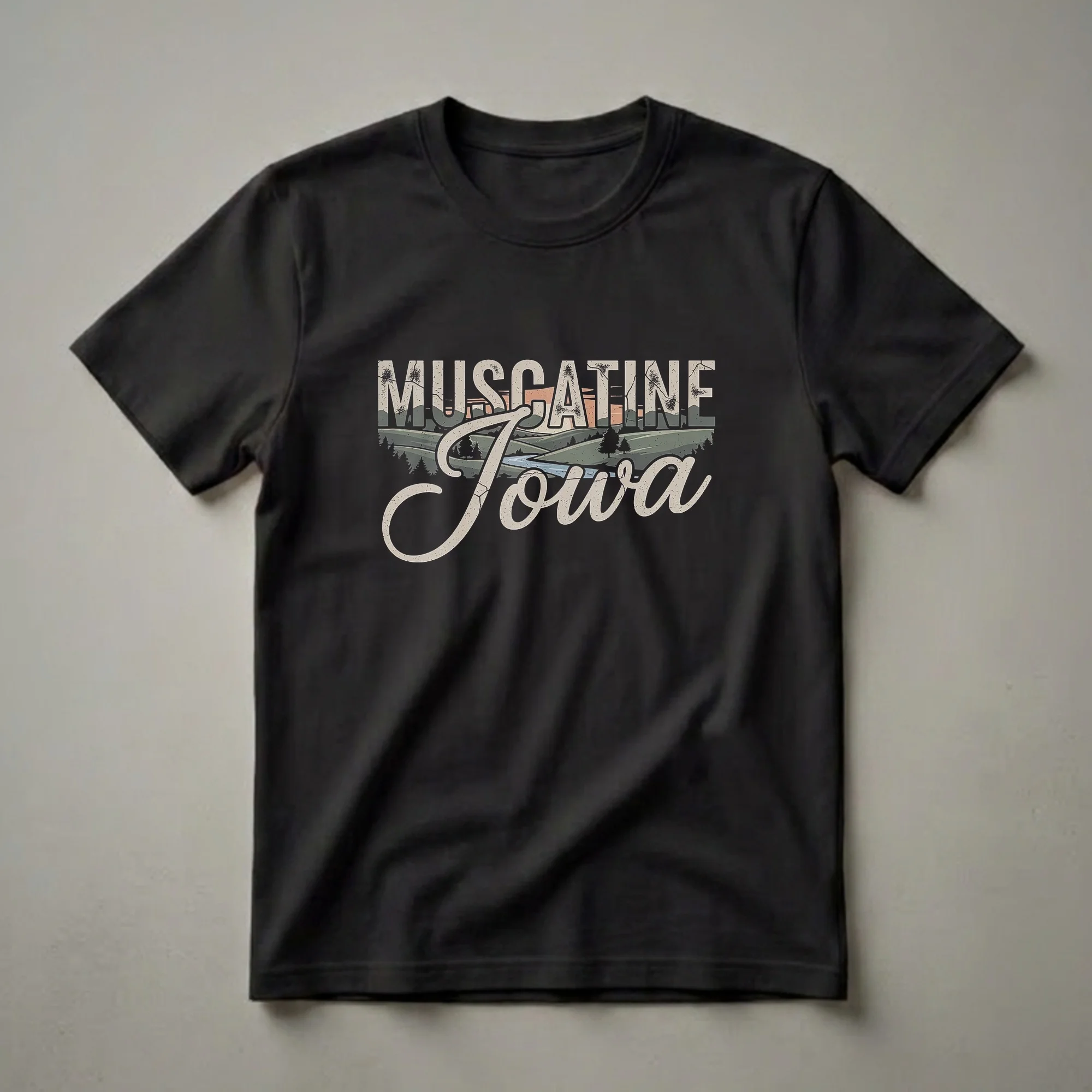 Black t-shirt featuring a retro graphic design with the words 'MUSCATINE Iowa' over a landscape of rolling hills, a river, and trees at sunset.