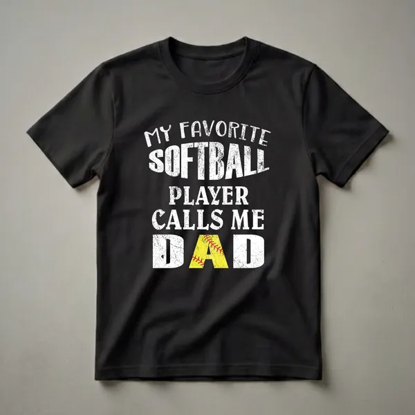 Black t-shirt with distressed white text that reads 'MY FAVORITE SOFTBALL PLAYER CALLS ME DAD', with the 'A' in DAD replaced by a yellow softball graphic.