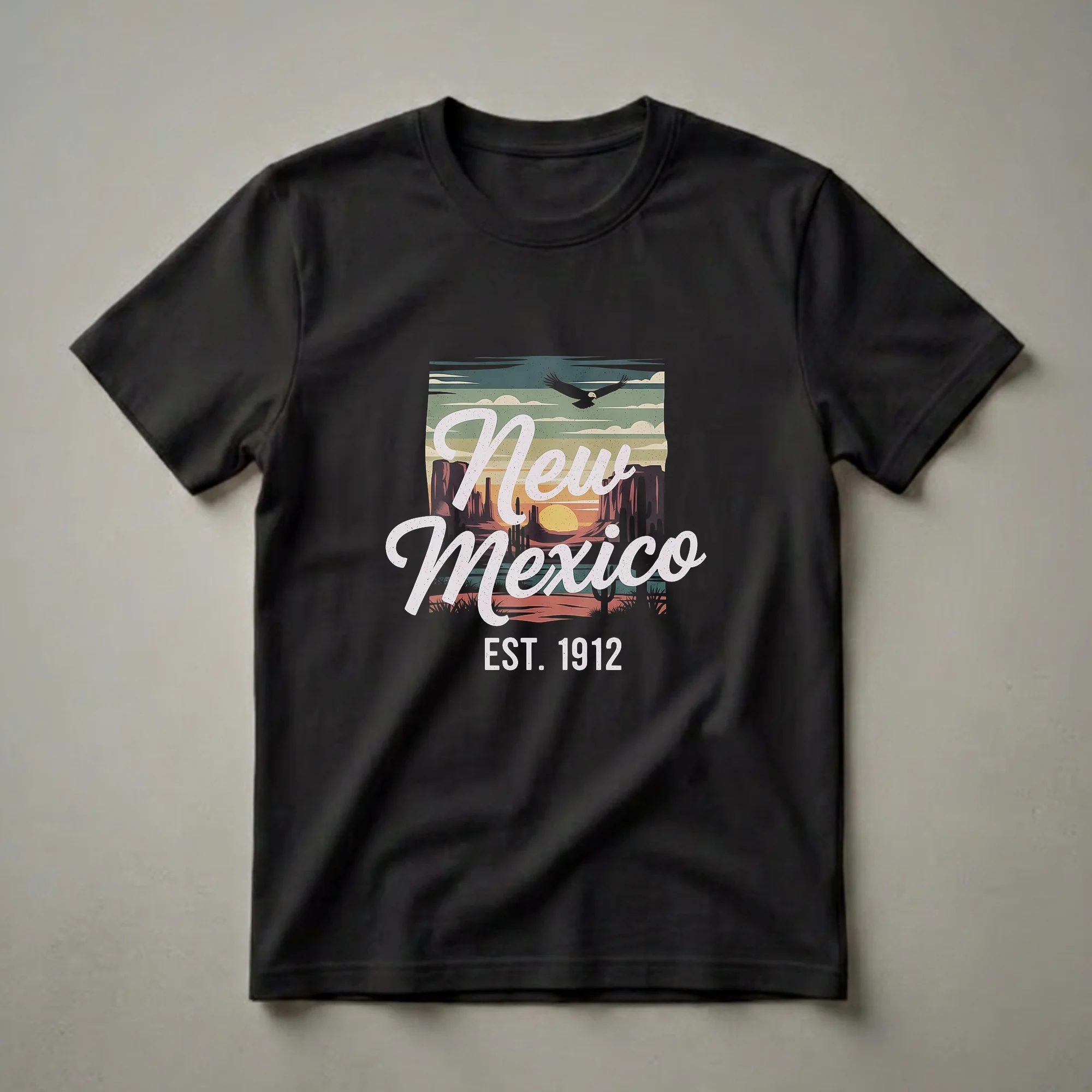 Black t-shirt featuring a retro graphic design of New Mexico with a desert landscape, sunset, and a soaring eagle. The text 'New Mexico EST. 1912' is prominently displayed.