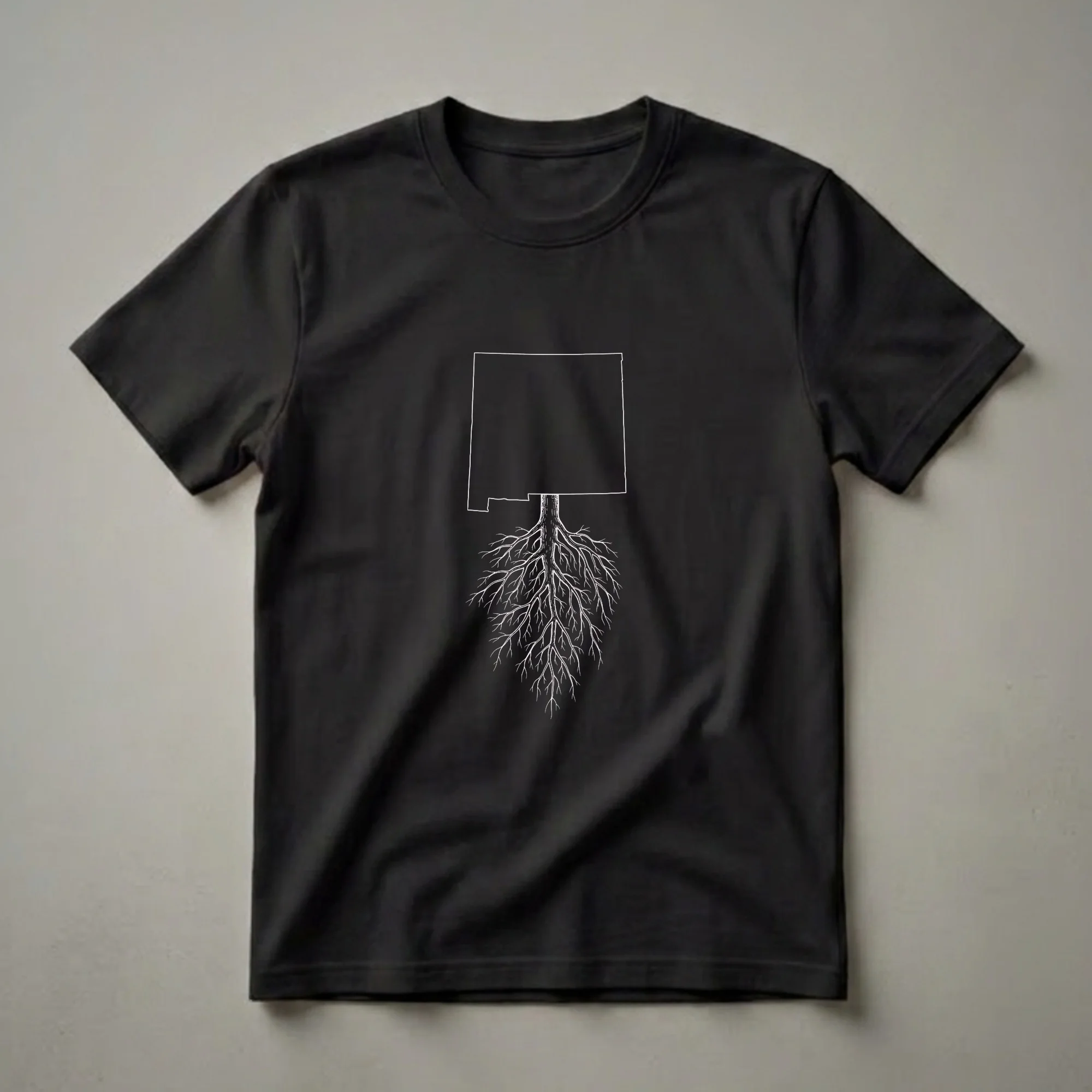 Black t-shirt with a white graphic depicting the outline of New Mexico with a tree trunk and extensive root system extending below.