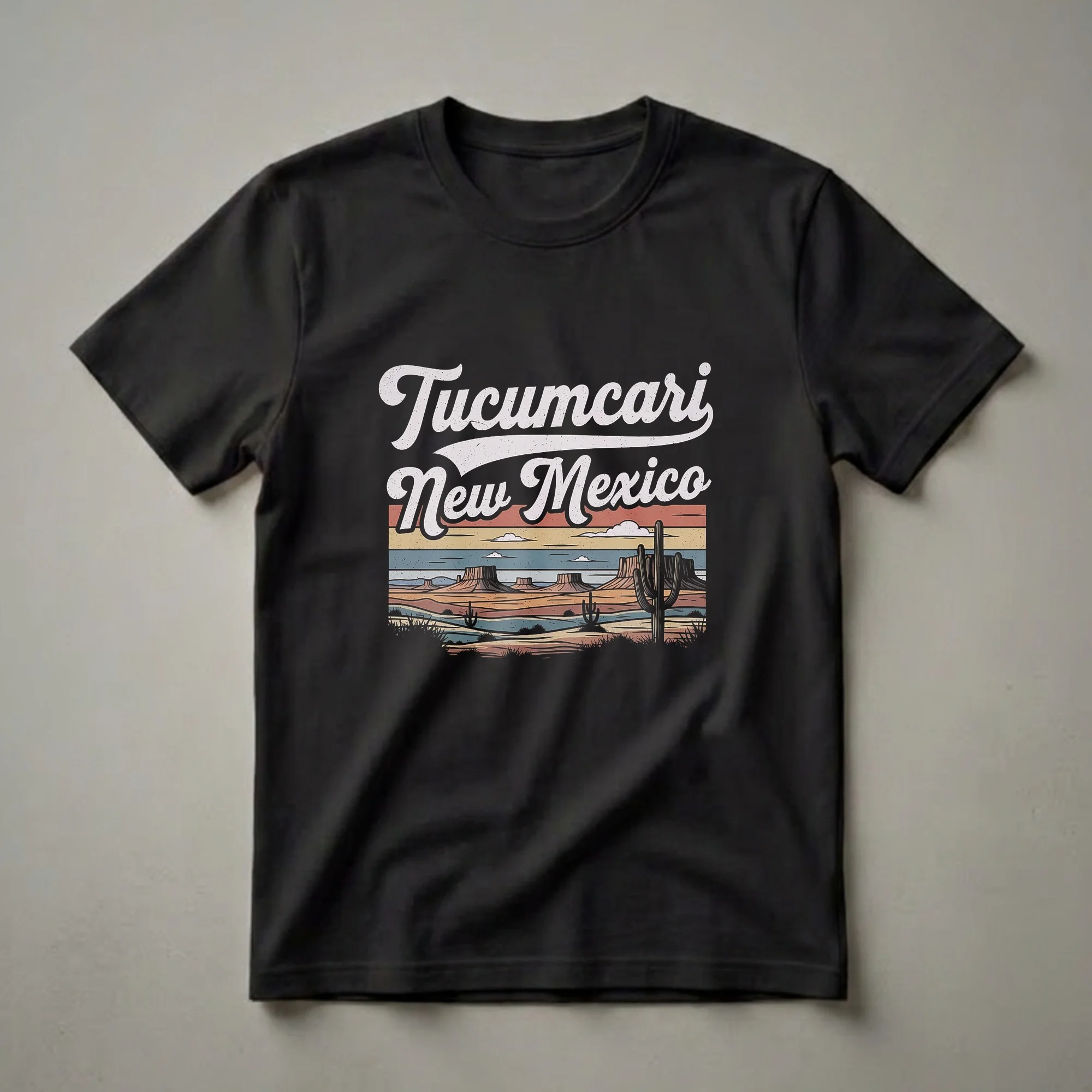 Black graphic t-shirt featuring a retro design of Tucumcari, New Mexico, with desert mesas, saguaro cacti, and a striped sunset sky.